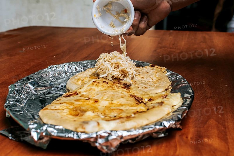 Traditional pupusas served with salad on the table. Nicaraguan pupusas with salad on aluminum foil