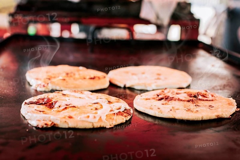 Traditional Salvadoran pupusas with melted cheese on a grill
