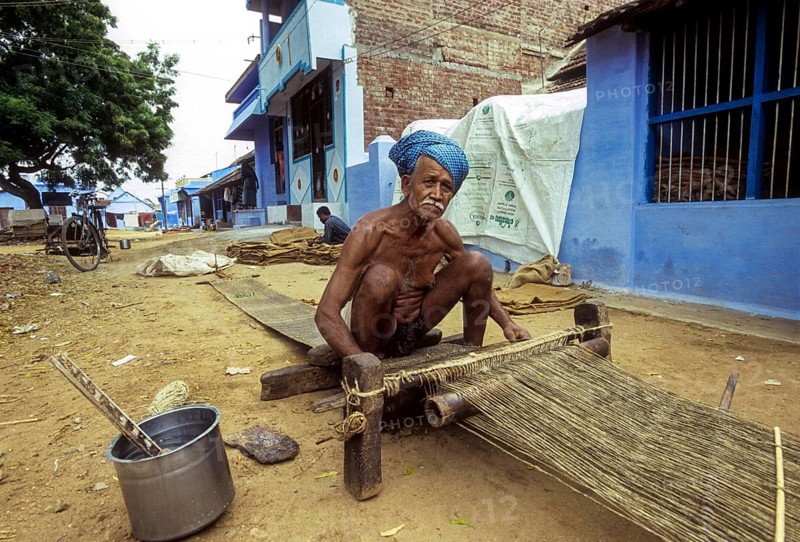 An old man weaving jute mats on the street at Tenkasi