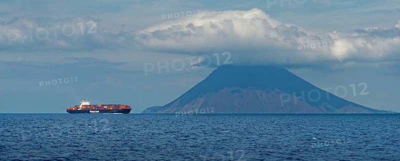 Container ship in front of the island and volcano Stromboli