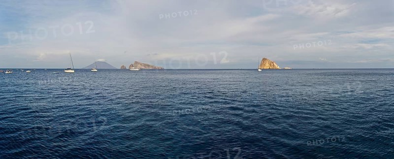 Le Guglie Island and di Basiluzzo of a former volcano and the volcanic island of Stromboli with anchored sailing ships