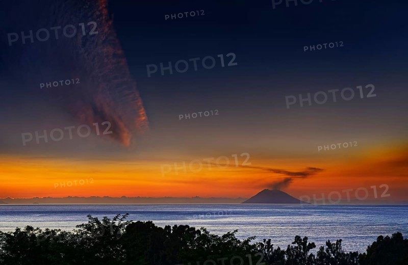 Strompoli volcano with plumes of smoke at sunset