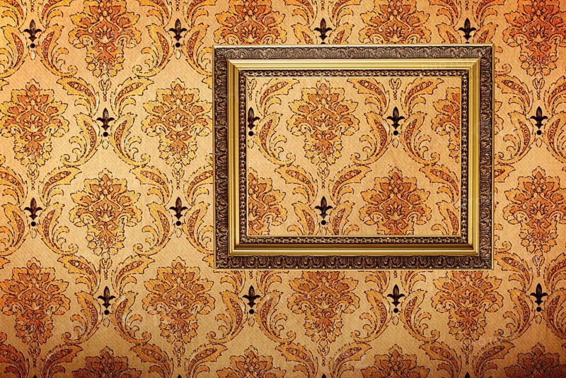 Vintage gold plated picture frame on retro wallpaper background