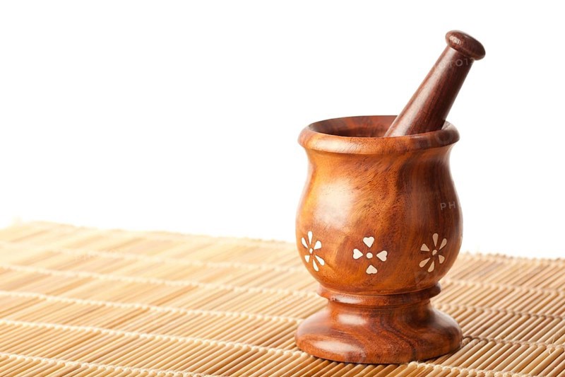Wooden mortar with pestle on bamboo mat