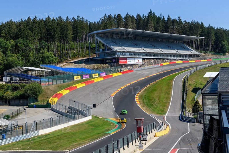 View of two Porsche GT3 racing cars racing through dangerous Eau Rouge bend onto 40-metre-high Raidillon slip road of Circuit de Spa Francorchamps