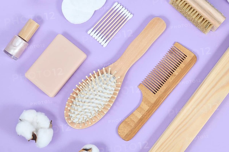 Eco friendly wooden beauty and hygiene items like comb and soap on purple background