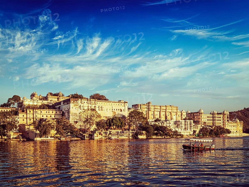 Vintage retro effect filtered hipster style image of City Palace and tourist boat on lake Pichola on sunset. Udaipur