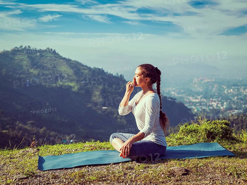 Vintage retro effect hipster style image of woman practices pranayama yoga breath control in lotus pose padmasana outdoors in Himalayas in the morning on sunrise. Himachal Pradesh