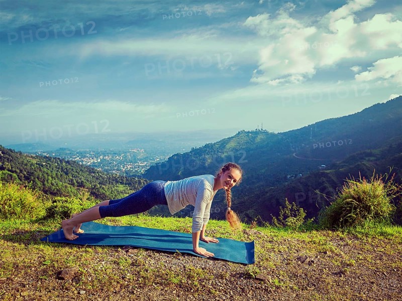 Vintage retro effect hipster style image of woman doing Hatha yoga asana Kumbhakasana plank pose outdoors in mountains