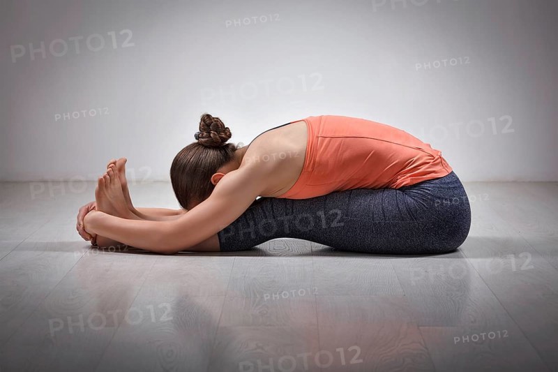Sporty fit woman practices Ashtanga Vinyasa yoga back bending asana Paschimottanasana