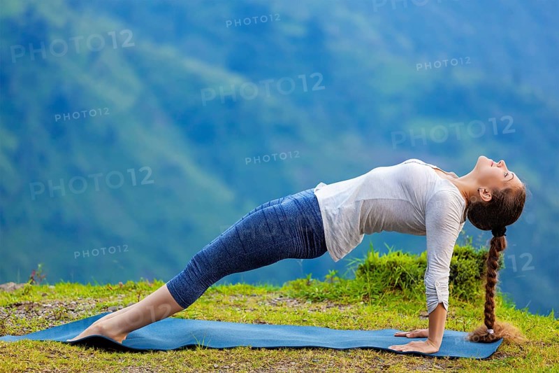 Woman doing Hatha yoga asana Purvottanasana plank pose outdoors in mountains