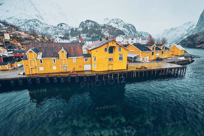 Panorama of Nusfjord authentic fishing village with yellow rorbu houses in Norwegian fjord in winter. Lofoten islands