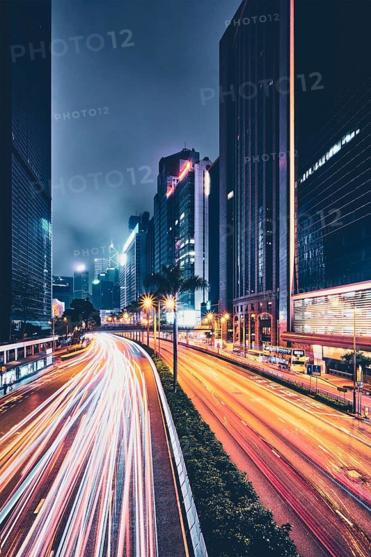 Street traffic in Hong Kong at night. Office skyscraper buildings and busy traffic on highway road with blurred cars light trails. Hong Kong