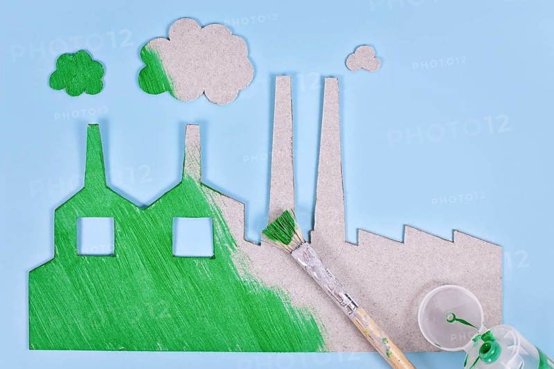 Greenwashing concept with cardboard factory being painted green