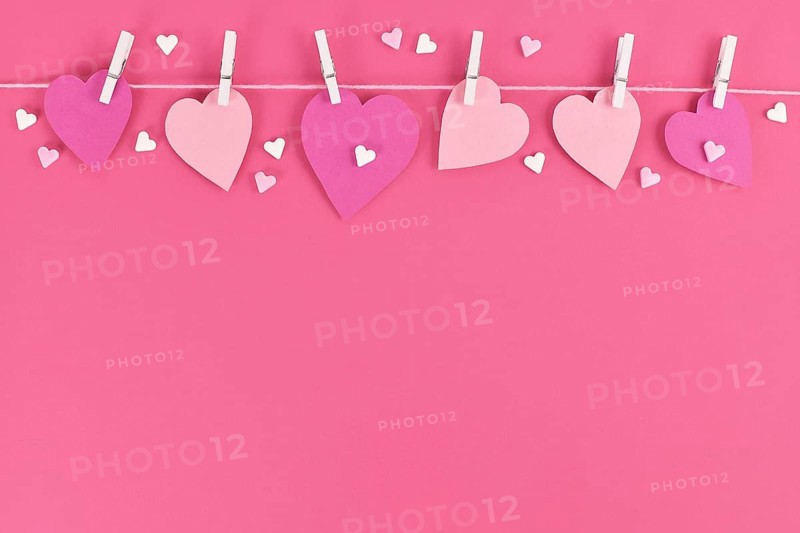 Pink paper hearts hanging from line with pegs and sugar sprinkles