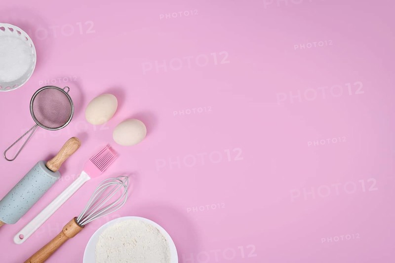 Cake dough ingredients and baking tools on pink background with copy space