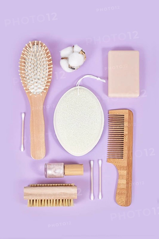 Eco friendly wooden beauty and hygiene products like comb and soap arranged on violet background