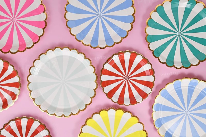 Colorful striped paper party plates on pink background