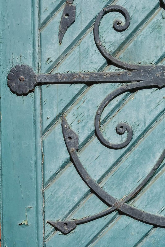 Old decorated iron door fitting on an old green wooden door