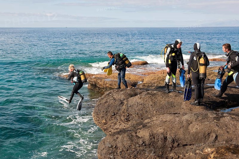 Diver entering sea from rocky coast