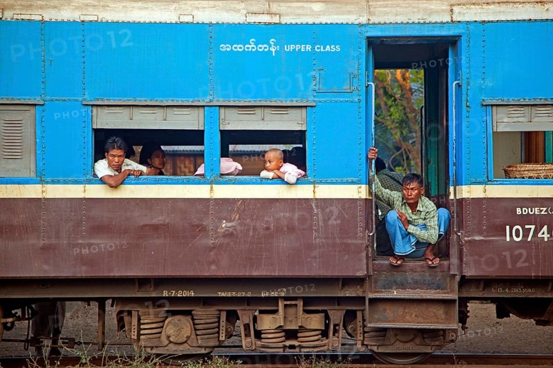 Burmese passengers in the blue upper class car of an old British train in Myanmar