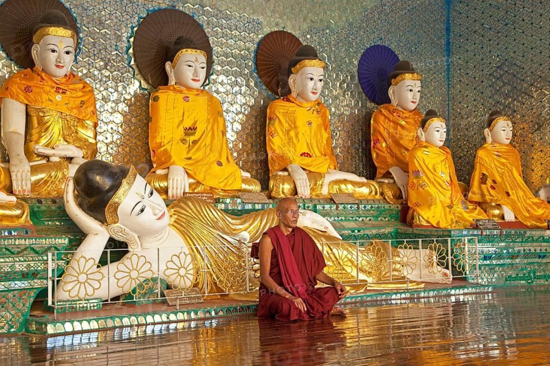 Buddhist monk praying in front of Buddha statues at the Shwedagon Zedi Daw Pagoda in Yangon