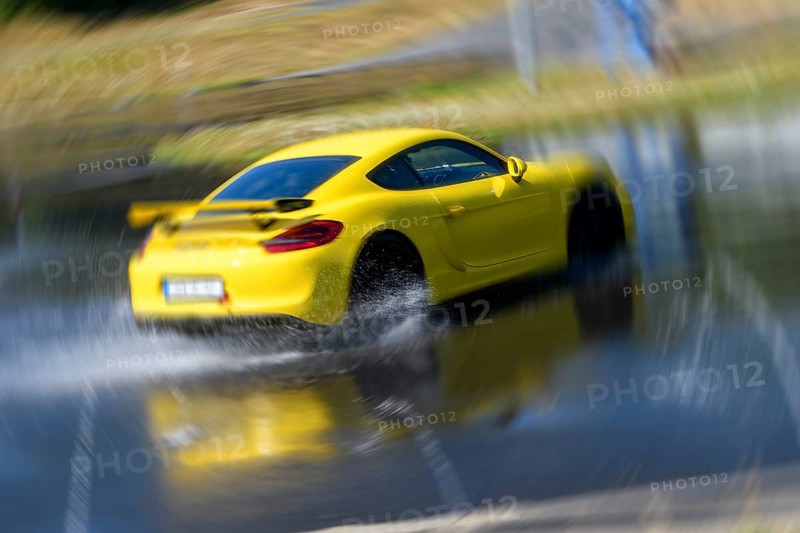 Sports car racing car Porsche Cayman GT4 on artificially rain wet road during driving safety training skids due to aquaplaning