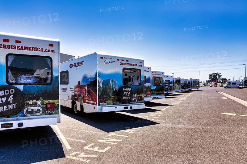 Many motorhomes with company logo are available for rent side by side in a company car park