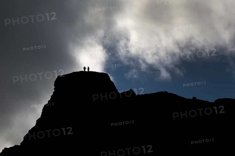 Dramatic sky with two people in front of clouds on a mountain in Kirkjubaejarklaustur