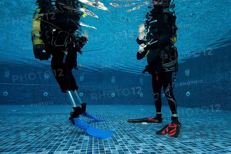Disabled diver with prosthetic legs and diving instructor