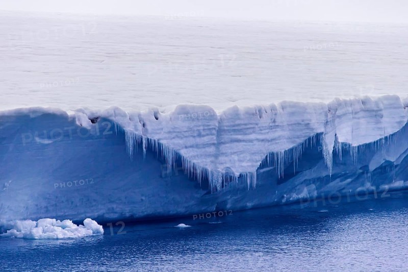 Icicles hanging from the ice wall of the melting Brasvellbreen glacier flowing into the Arctic Ocean
