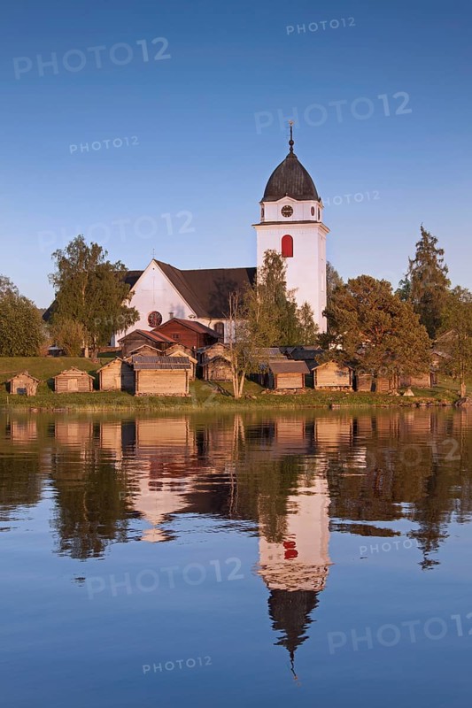 The picturesque old church of Raettvik surrounded by horse stables at Lake Siljan
