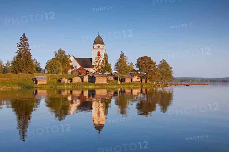 The picturesque old church of Raettvik surrounded by horse stables at Lake Siljan