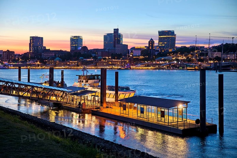 Pier for the harbour ferries at the Stage Theater on the Elbe in the evening in front of the city skyline