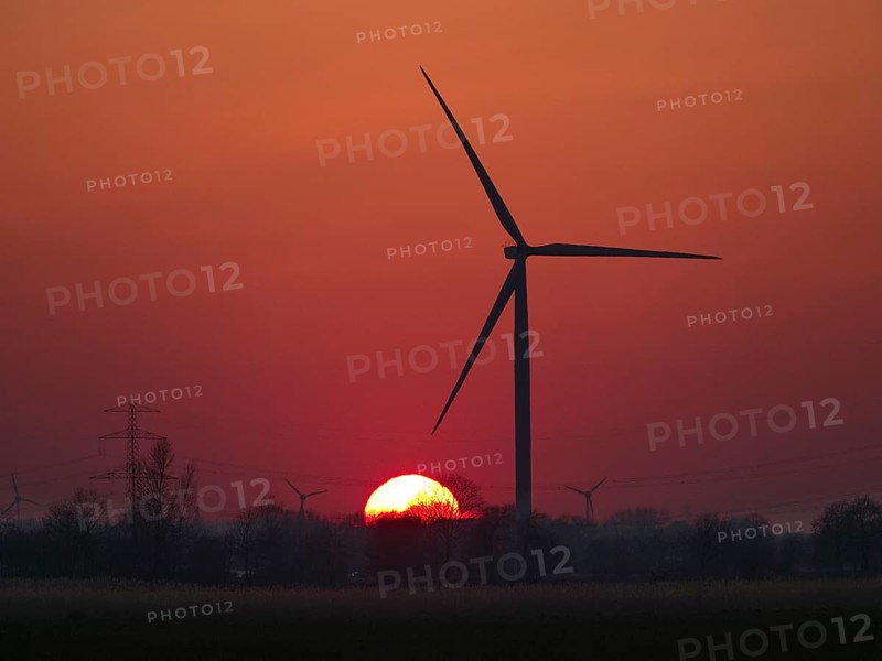 Wind turbines and power lines in front of the setting sun in Hamburg's Vier- und Marschlanden. Ochsenwerder