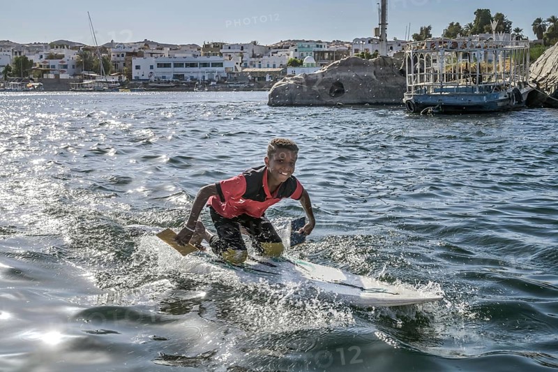 Boy on surfboard sings songs to tourists for money
