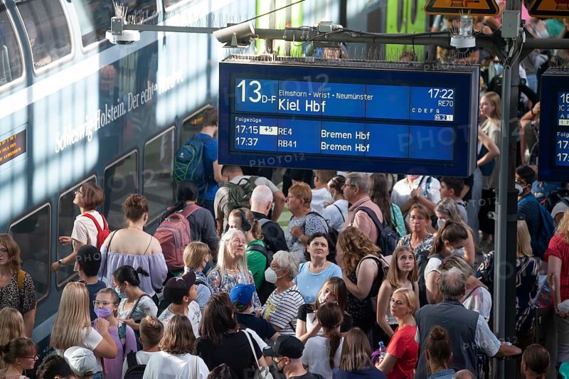 Many people standing crowded on a platform in front of a local train