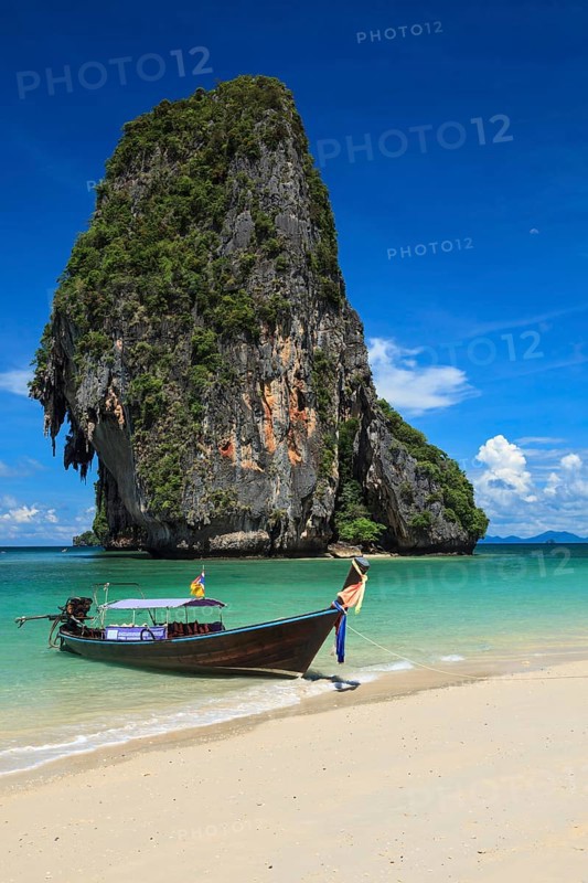 Long tail boat on tropical beach with limestone rock