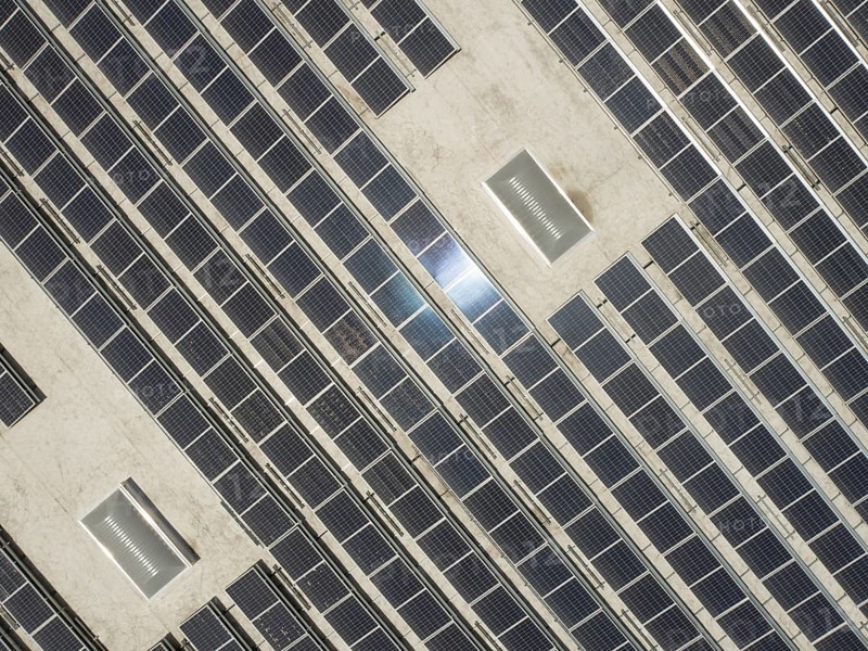 Aerial view of solar panels mounted on roof of large industrial building or warehouse