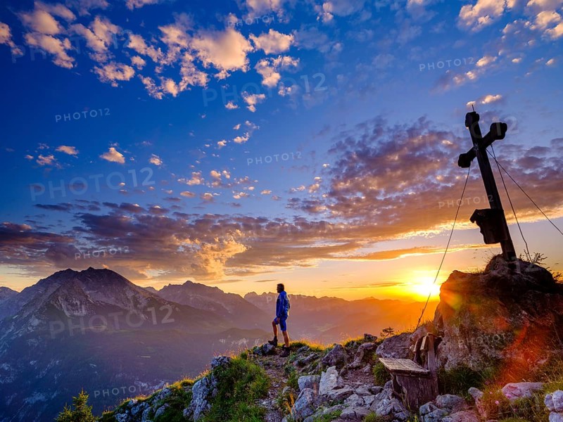 Mountaineer standing at sunset at the summit cross of the Brettgabel