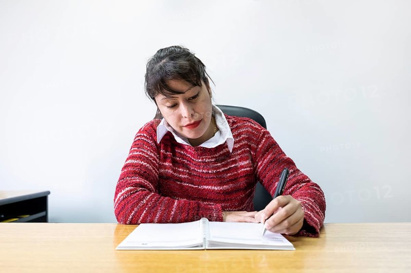Latin business woman sitting at her desk taking notes