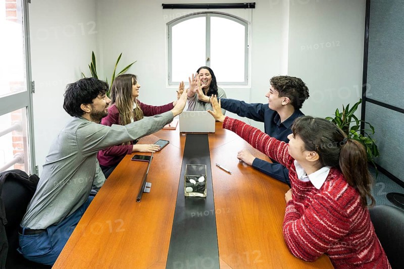 Cheerful office workers giving high five to colleagues