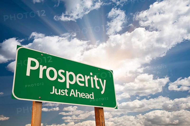 Prosperity green road sign over sunny dramatic clouds and sky