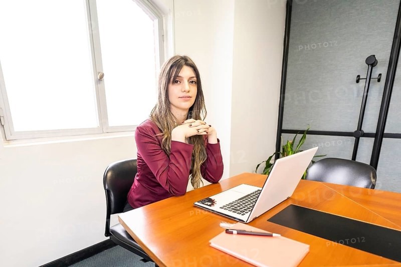 Young blonde business woman sitting at the head of the table in the office meeting room