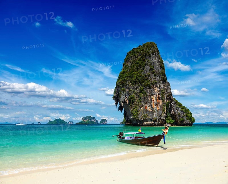 Long tail boat on tropical beach with limestone rock