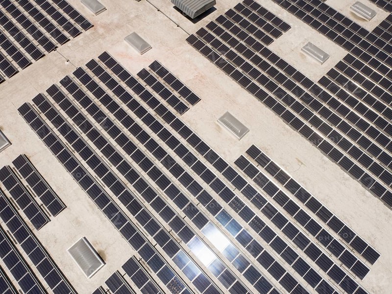 Aerial view of solar panels mounted on roof of large industrial building or warehouse