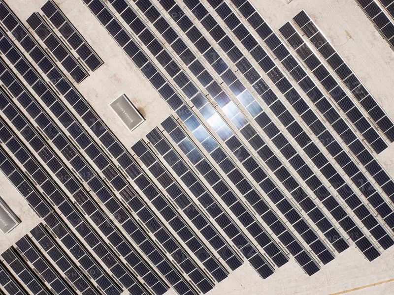 Aerial view of solar panels mounted on roof of large industrial building or warehouse