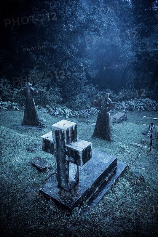 Spooky Halloween graveyard in fog in moonlight