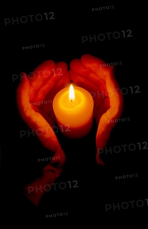 Wax candle burning between 2 hands