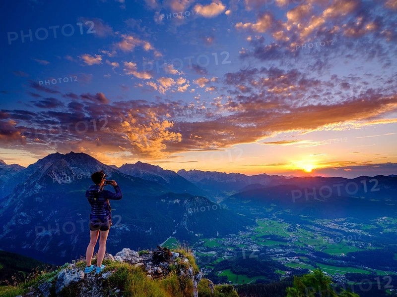 Mountaineer taking pictures of sunset with mobile phone